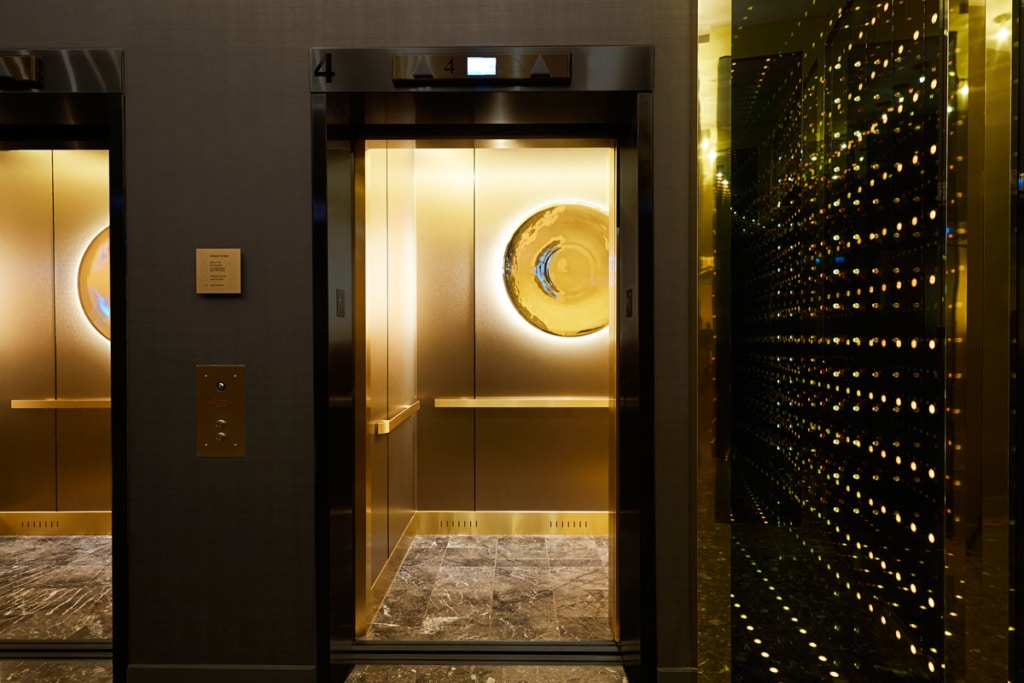 Ground level elevator lobby with custom infinity mirror feature and elevator cab with back-lit mirror artwork by Toronto-based artist
