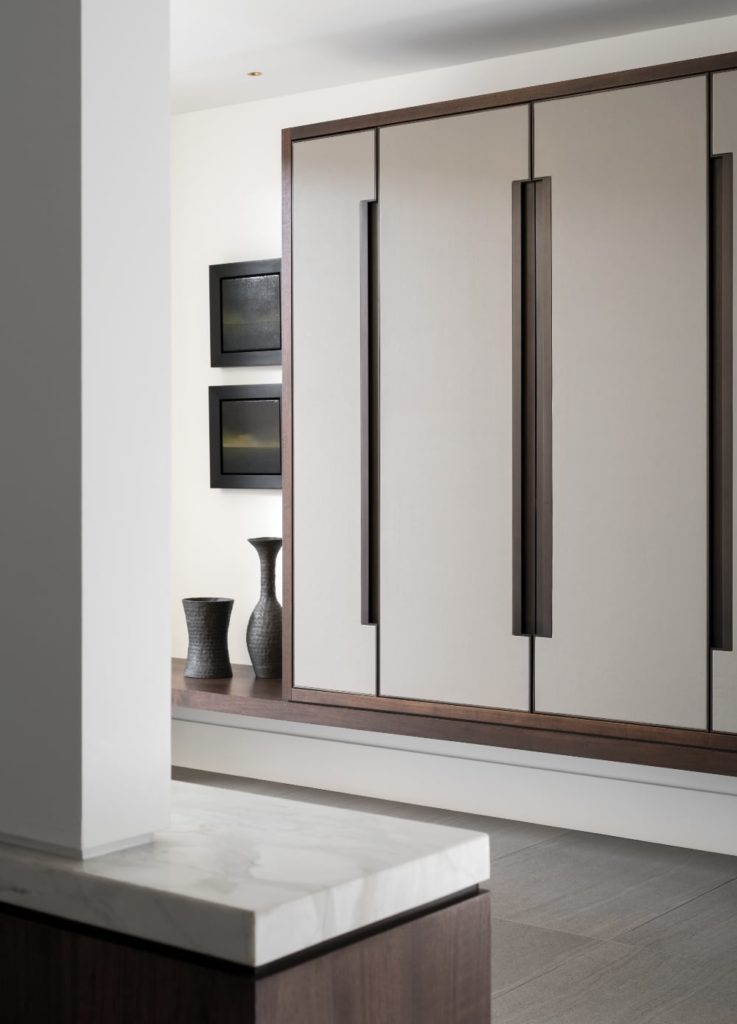 Built-in millwork, combining walnut, lacquered wood and custom closet doors of leather trimmed in bronze